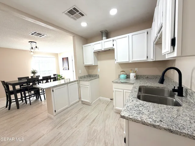 a kitchen with granite countertop white cabinets and sink