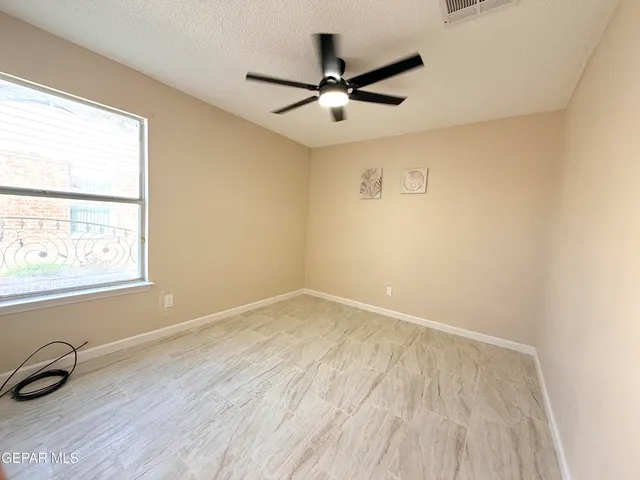 an empty room with a window and a ceiling fan