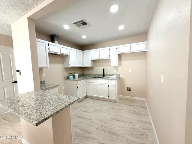 a kitchen with granite countertop white cabinets and refrigerator