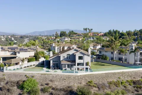 a view of a big house with a big yard and large trees