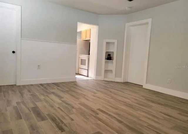 an empty room with wooden floor and windows