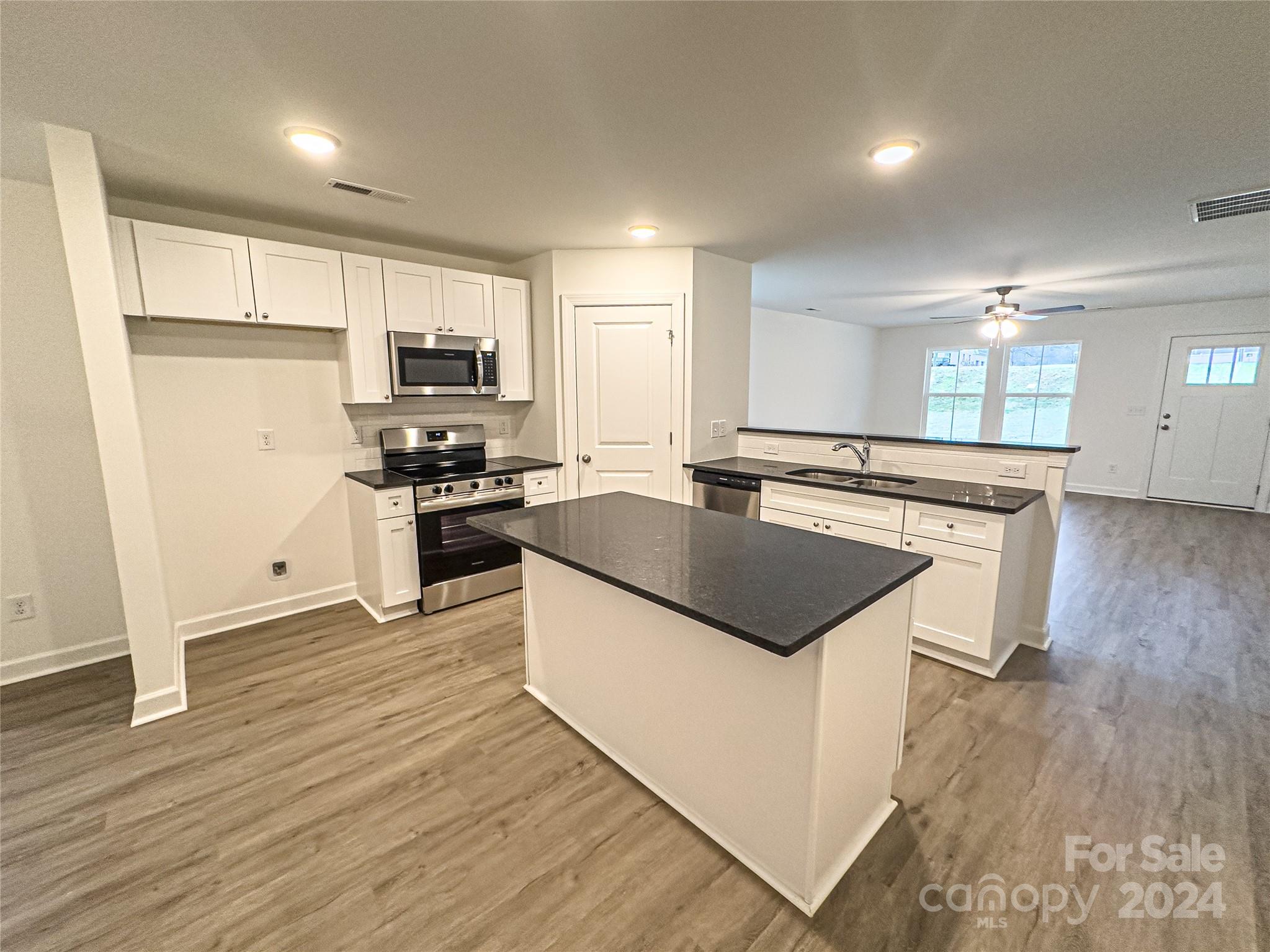650 Sedgefield Street Southwest Concord, NC 28025 - Photo 3 of 15 a kitchen with kitchen island a sink a stove a refrigerator and a microwave