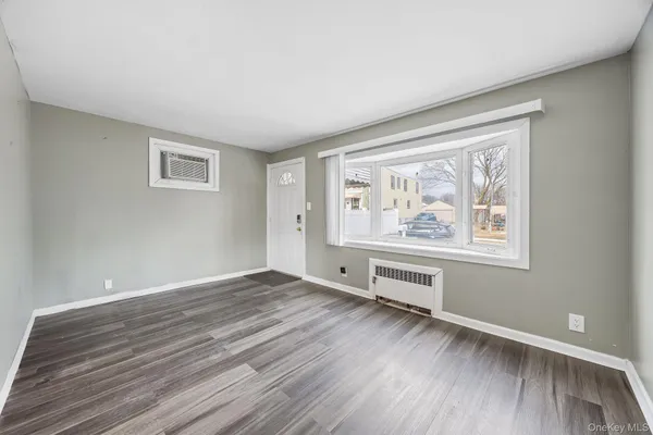 a view of an empty room with window and wooden floor