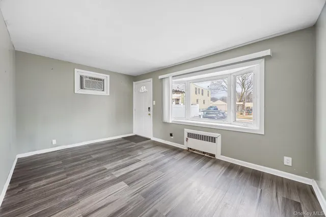 a view of an empty room with window and wooden floor
