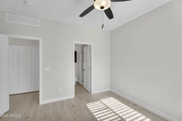 an empty room with a window and a ceiling fan