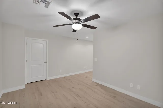a view of empty room with wooden floor and ceiling fan