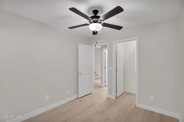 a view of empty room with wooden floor and fan