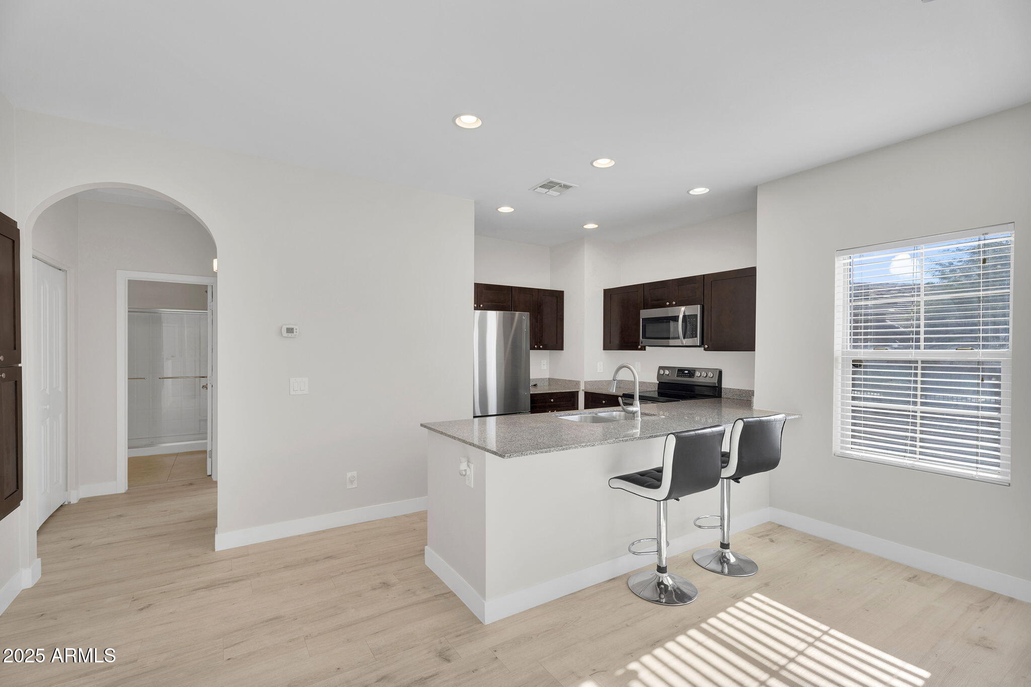 854 South San Marcos Drive, Unit 7C Apache Junction, AZ 85120 - Photo 6 of 48 a kitchen with stainless steel appliances kitchen island granite countertop a refrigerator and a stove top oven with wooden floor