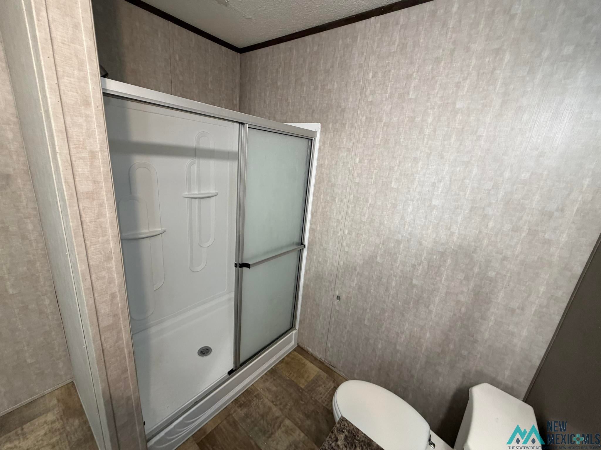 801 Riata Road Carlsbad, NM 88220 - Photo 35 of 39 Shower enclosure with sliding frosted glass doors, integrated shelving, and a white basin