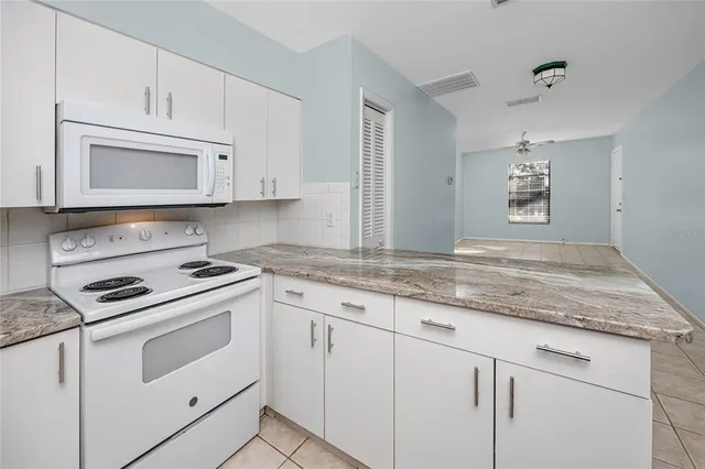 a kitchen with granite countertop white cabinets and white appliances
