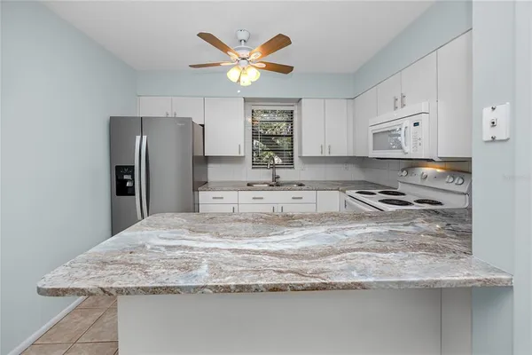 a kitchen with stainless steel appliances granite countertop a sink a refrigerator and a stove