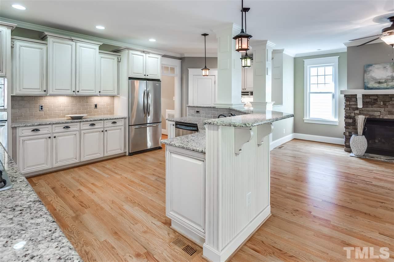 4214 Batiste Road Raleigh, NC 27613 - Photo 12 of 25 a kitchen with stainless steel appliances granite countertop a refrigerator a stove oven and white cabinets with wooden floors
