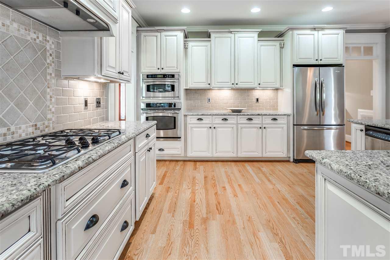 4214 Batiste Road Raleigh, NC 27613 - Photo 13 of 25 a kitchen with kitchen island granite countertop white cabinets and refrigerator