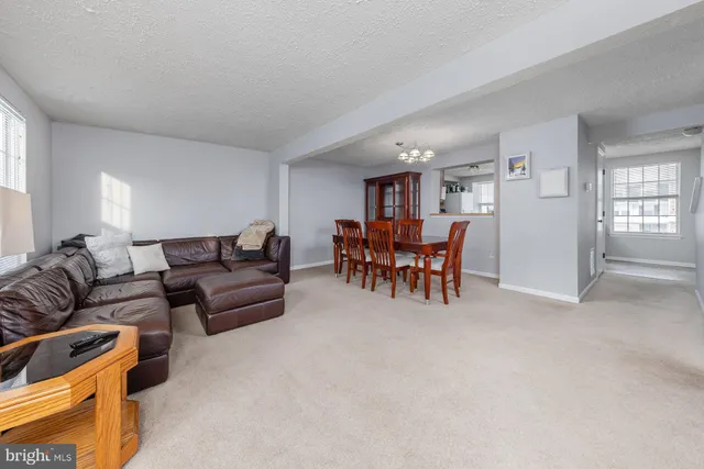 a living room with furniture and a dining table with kitchen appliances