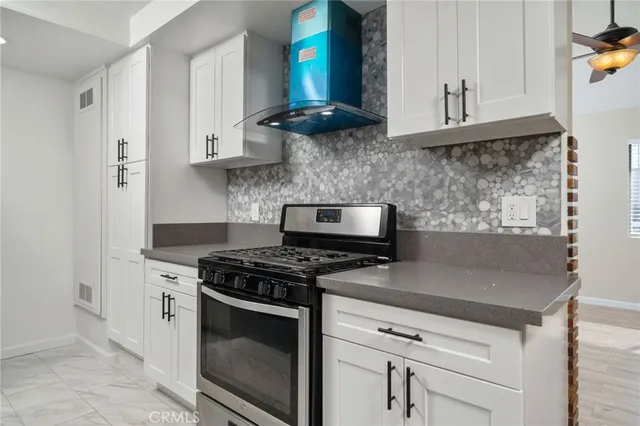a kitchen with stainless steel appliances granite countertop white cabinets a stove a sink and dishwasher