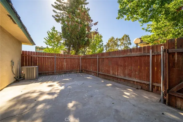 a view of a backyard with wooden fence and large trees
