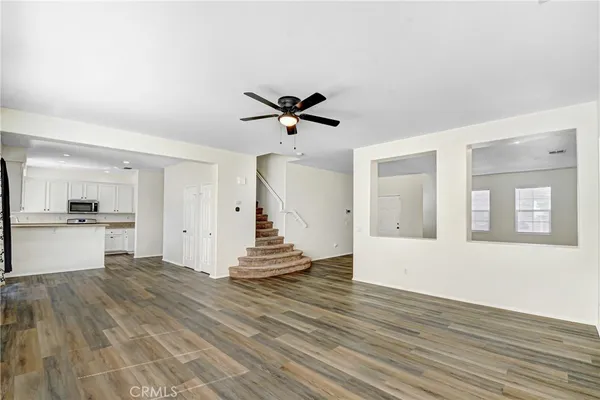 a view of an empty room with wooden floor and a kitchen