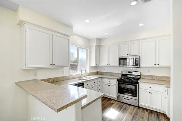 a kitchen with granite countertop a sink cabinets and stainless steel appliances