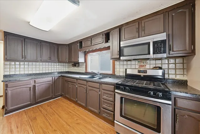 a kitchen with stainless steel appliances a stove sink microwave and cabinets