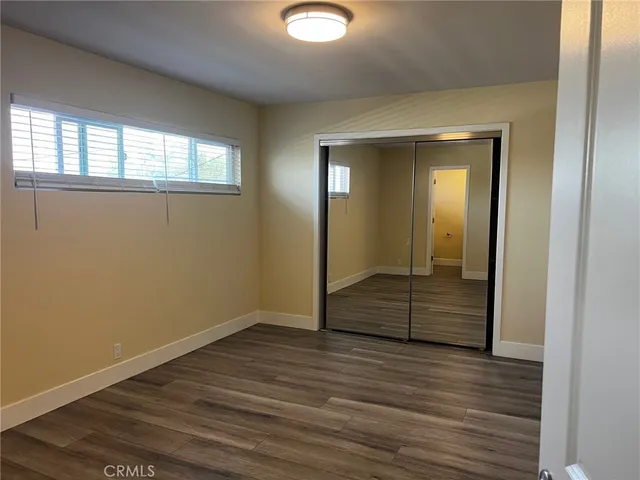an empty room with wooden floor and mirror