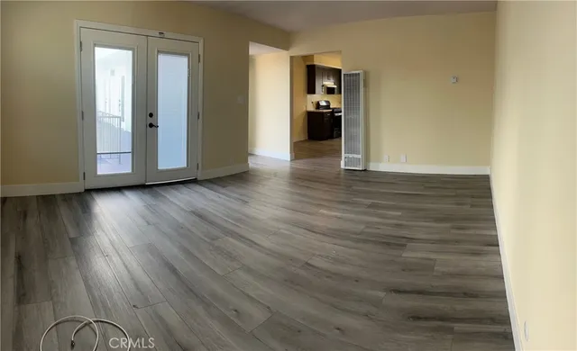 a view of an empty room with wooden floor and a window