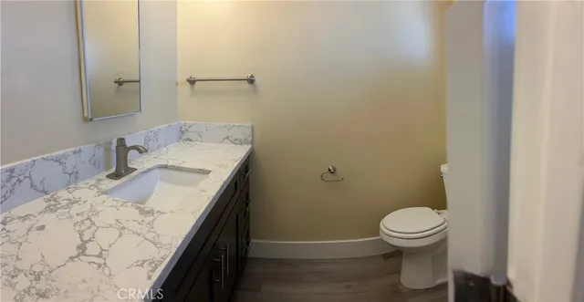 a bathroom with a granite countertop sink a toilet and a mirror