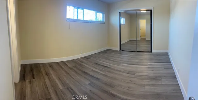 an empty room with wooden floor and mirror