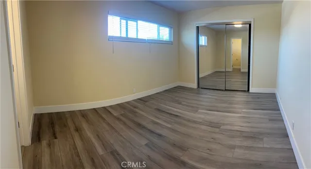 a view of an empty room with wooden floor and a mirror