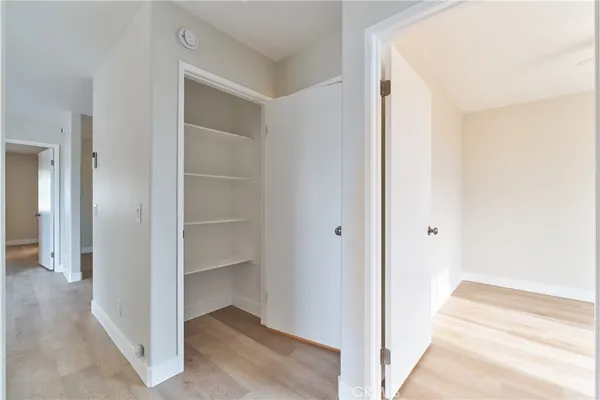 a view of an empty room with wooden floor and closet