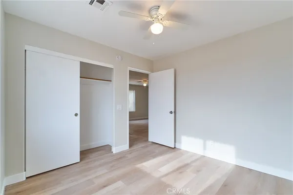an empty room with wooden floor and ceiling fan