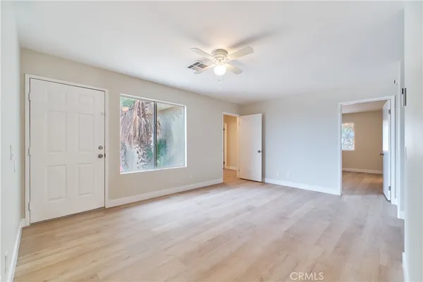 a view of an empty room with window and wooden floor