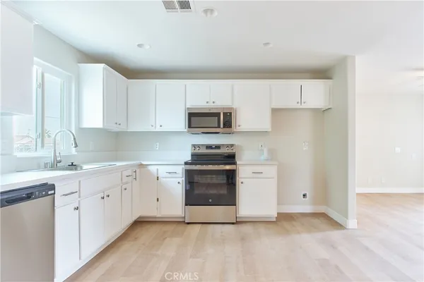 a kitchen with white cabinets and stainless steel appliances
