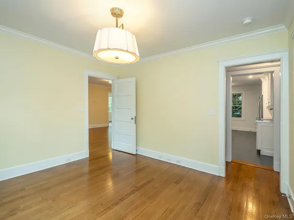 an empty room with wooden floor mirror and windows