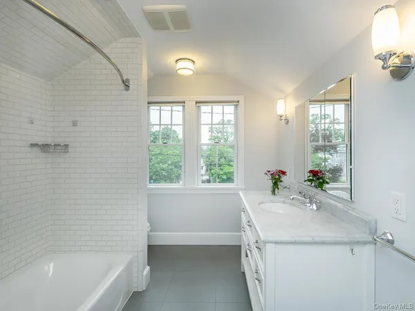 a bathroom with a granite countertop sink a bathtub and window