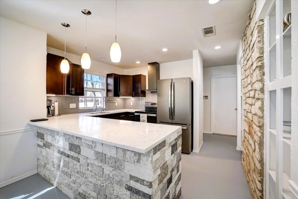 a large kitchen with stainless steel appliances kitchen island a large counter top and a refrigerator