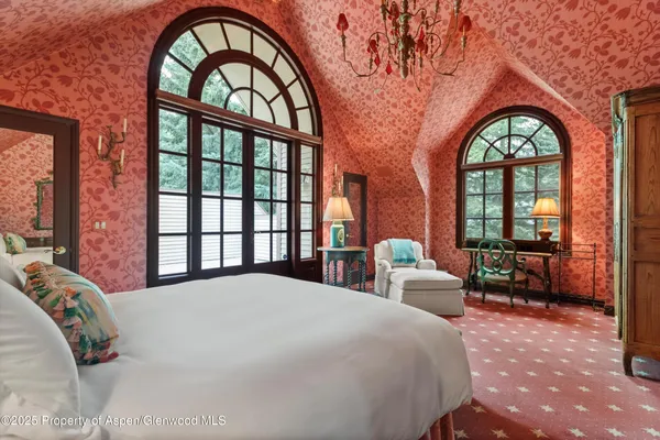 a bedroom with a large bed and windows