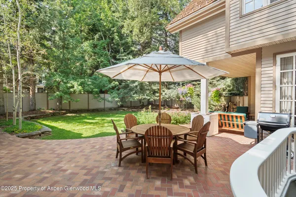 a view of a patio with a dining table and chairs under an umbrella