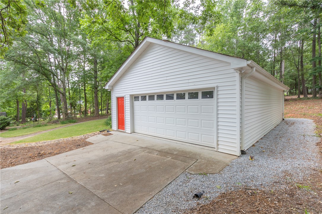 203 Oak Hollow Pendleton, SC 29670 - Photo 46 of 50 A detached garage offers ample storage and parking amidst a verdant, wooded landscape.