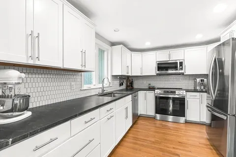 a kitchen with granite countertop a sink stainless steel appliances and cabinets