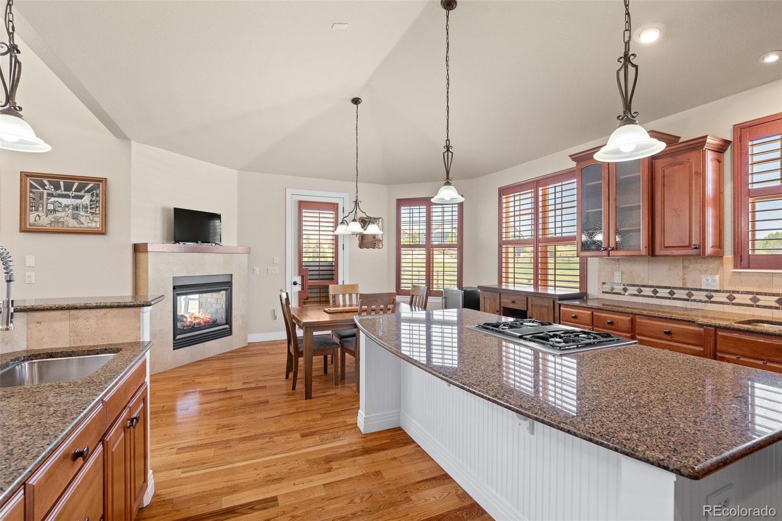 41865 East Muirfield Loop Elizabeth, CO 80107 - Photo 15 of 50 a kitchen with stainless steel appliances granite countertop a stove a sink a oven a dining table and chairs with wooden floor