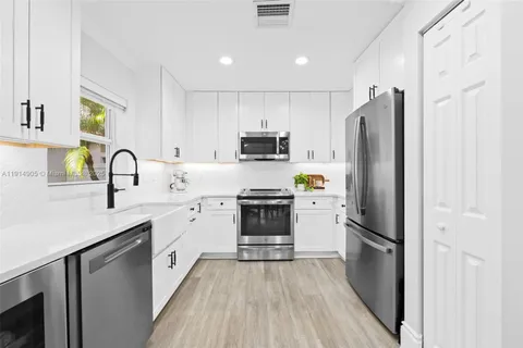a kitchen with granite countertop a refrigerator stove and sink