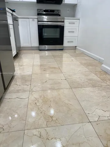 a kitchen with white cabinets and black appliances