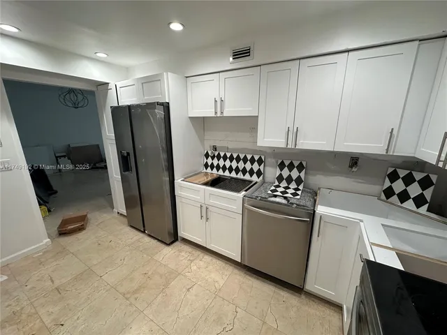 a living room with stainless steel appliances furniture a rug and a view of living room
