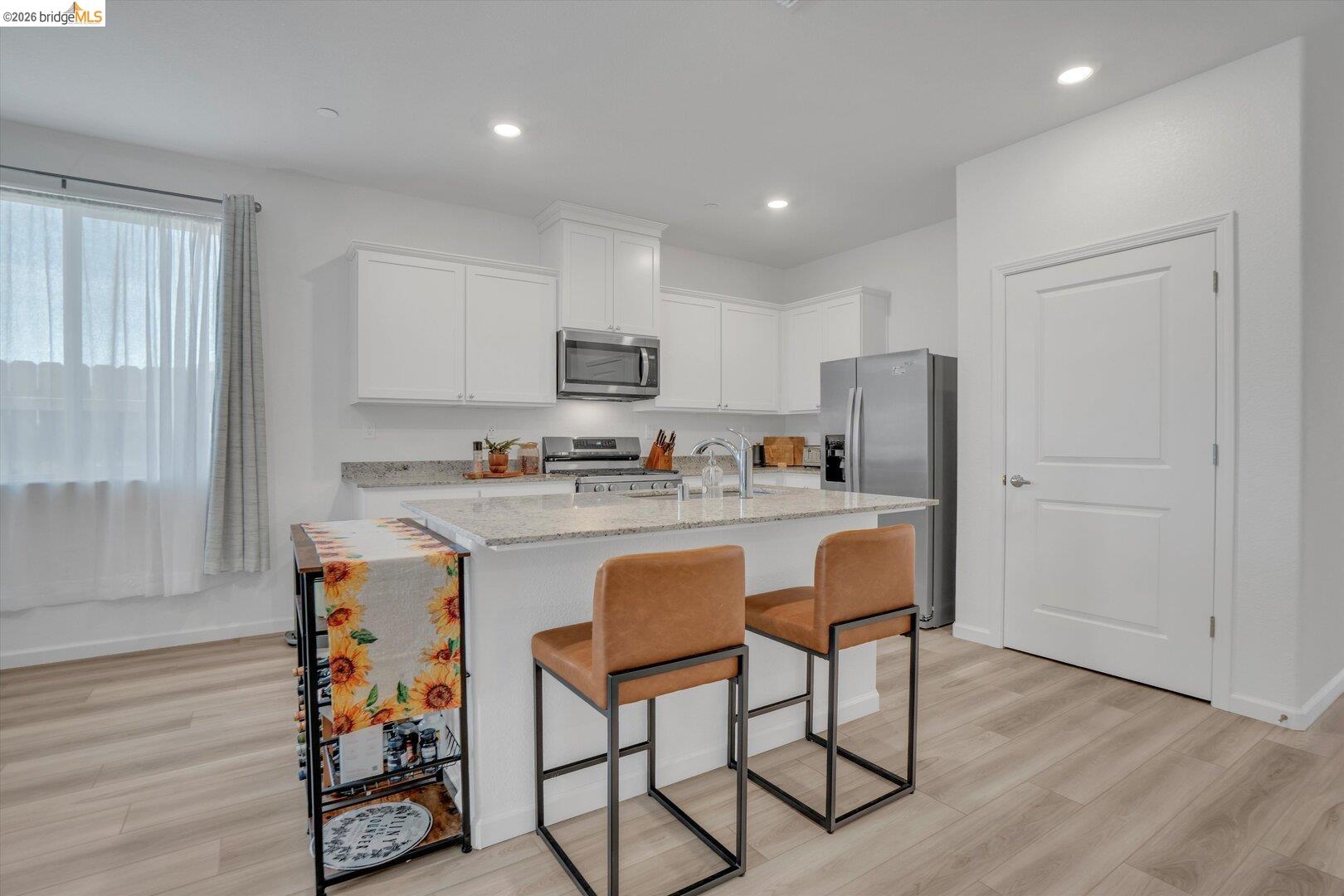 4463 Canada Way Rio Vista, CA 94571 - Photo 11 of 36 kitchen featuring light stone countertops, white cabinets, stainless steel appliances, a breakfast bar area, and a kitchen island with sink