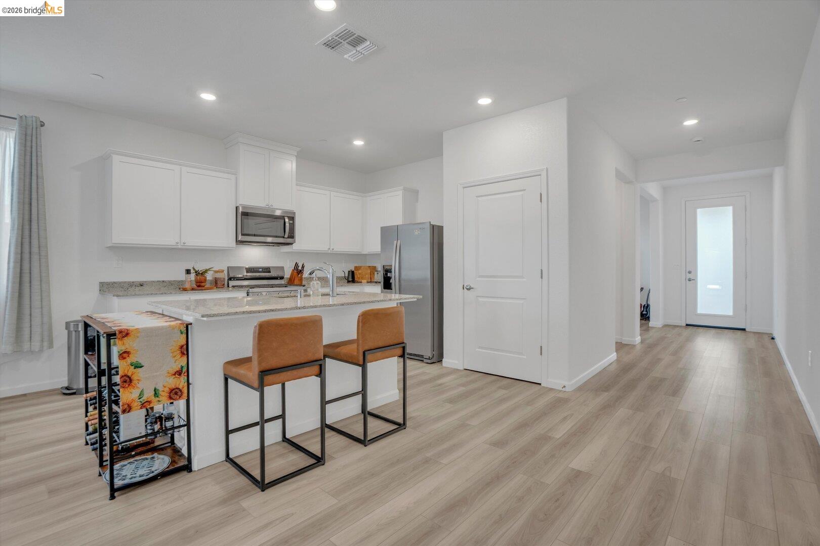 4463 Canada Way Rio Vista, CA 94571 - Photo 10 of 36 kitchen with a breakfast bar, light stone countertops, white cabinetry, stainless steel appliances, and light wood-type flooring