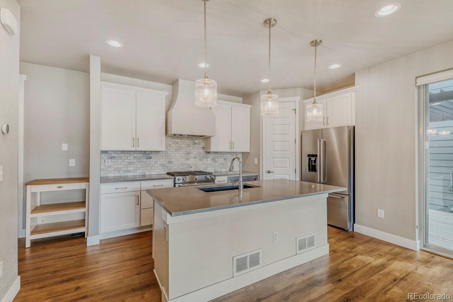 6850 Decatur Street Denver, CO 80221 - Photo 9 of 30 a large kitchen with cabinets wooden floor and a stainless steel appliances