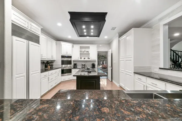 a large kitchen with stainless steel appliances kitchen island granite countertop a refrigerator and a stove top oven