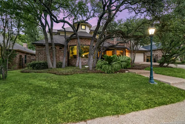 a yellow house with a big yard and large trees