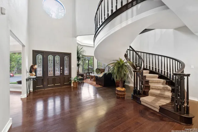 a hallway with wooden floor stairs and windows