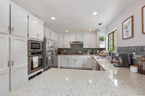 a kitchen with granite countertop a refrigerator stove top oven and sink